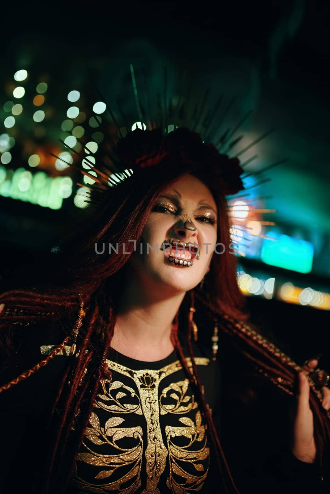 Girl with skeleton makeup at a Halloween party make grimaces and looks at camera. Celebration in a nightclub. Female in creepy costume of Mexican goddess of death. All Saints' Night.