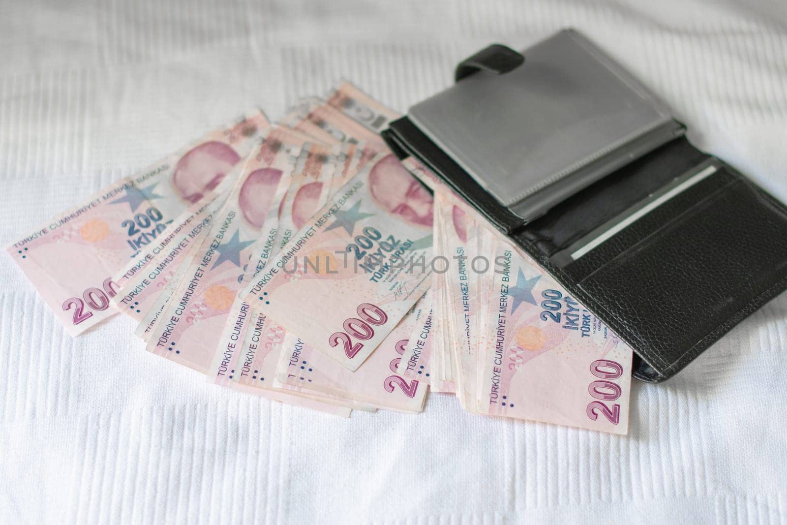 pack of Turkish liras spills out of a black wallet, a full wallet with a face value of 200 Turkish liras on a white background,giving up cash and switching to non-cash payments