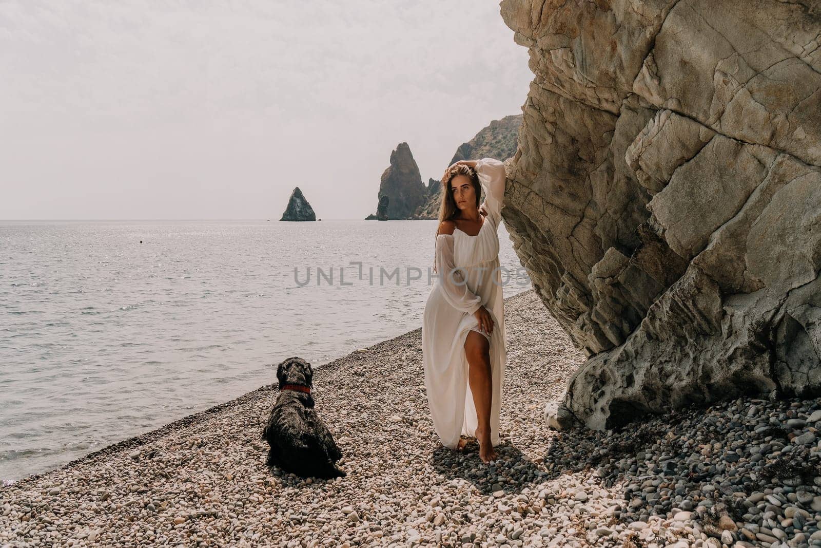 Woman travel sea. Young Happy woman in a long red dress posing on a beach near the sea on background of volcanic rocks, like in Iceland, sharing travel adventure journey