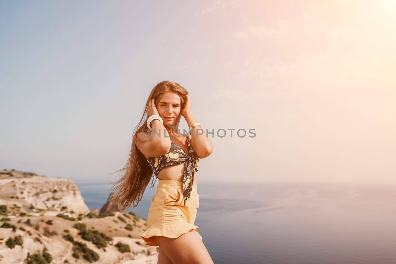 Woman travel sea. Happy tourist taking picture outdoors for memories. Woman traveler looks at the edge of the cliff on the sea bay of mountains, sharing travel adventure journey.