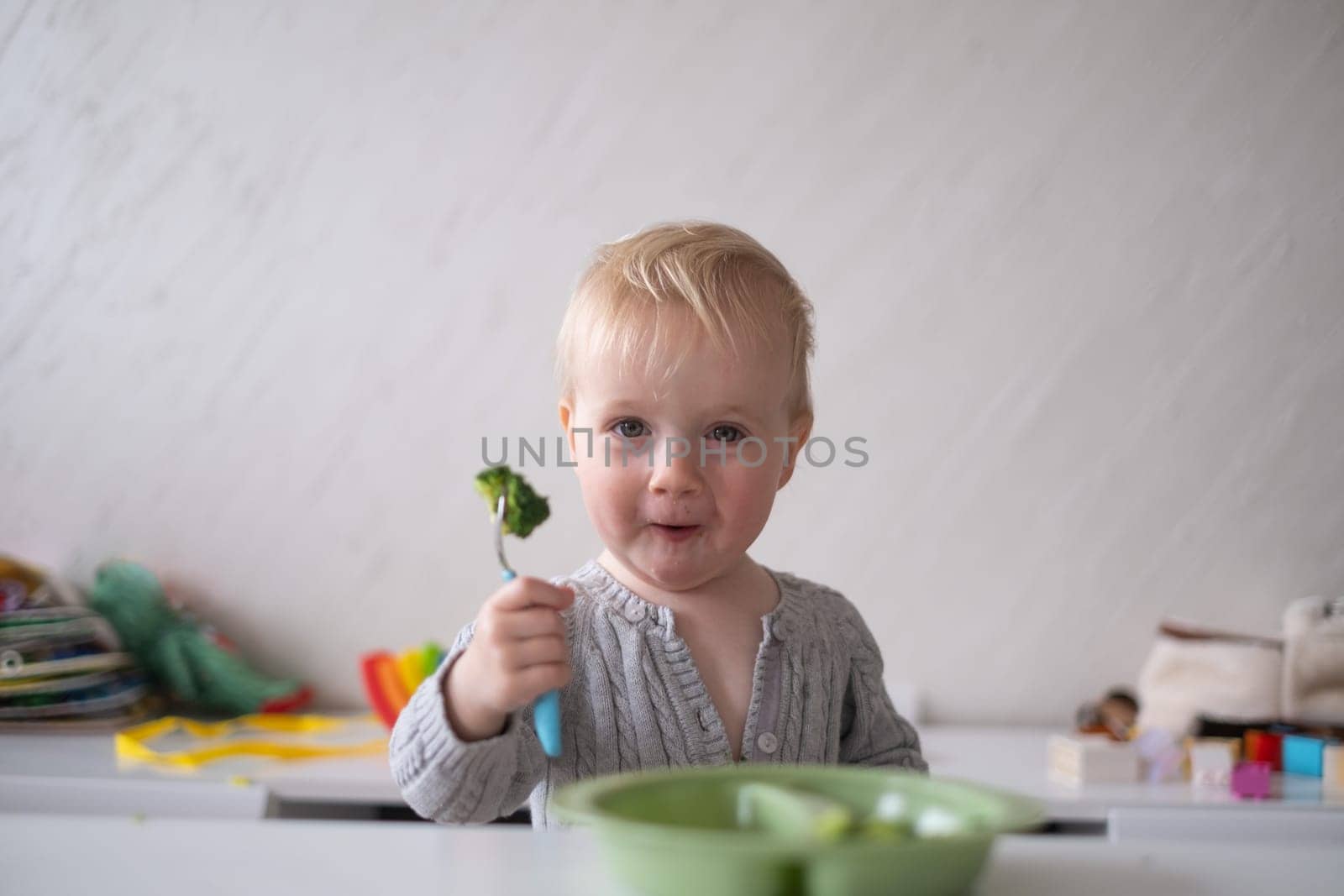 Caucasian little girl eats vegetable salad using fork.