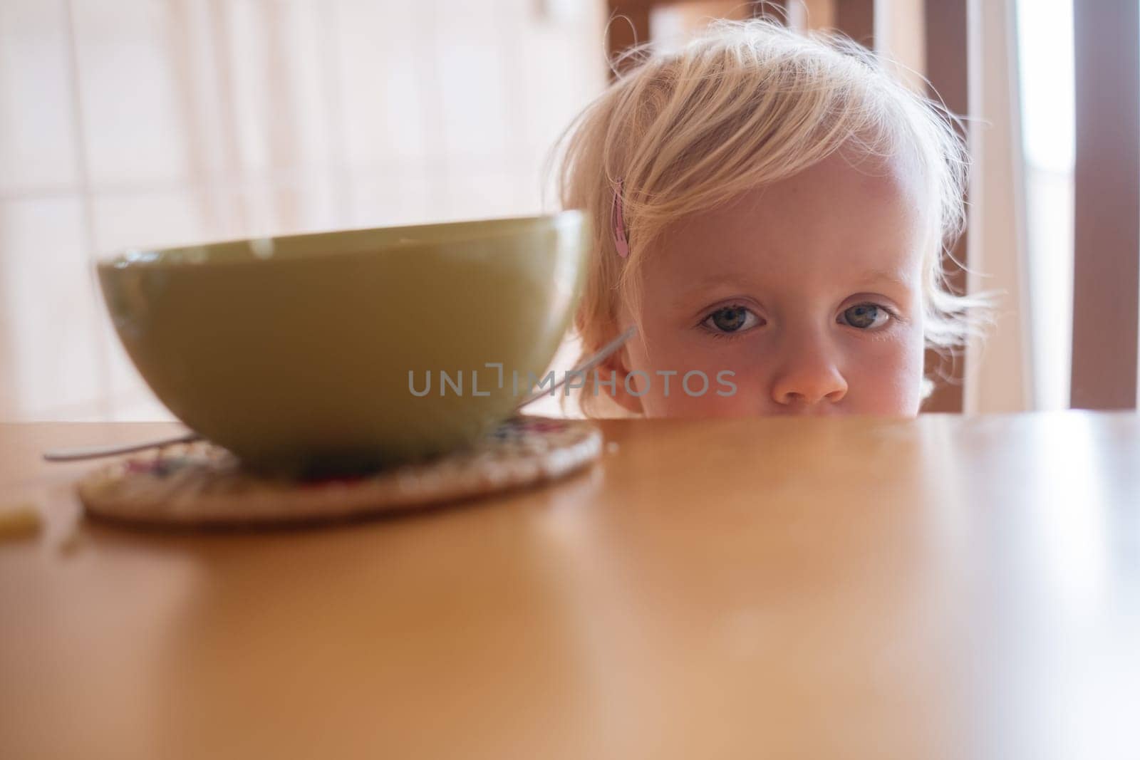 Beautiful blond child eating and crying with tantrum at home.. High quality photo