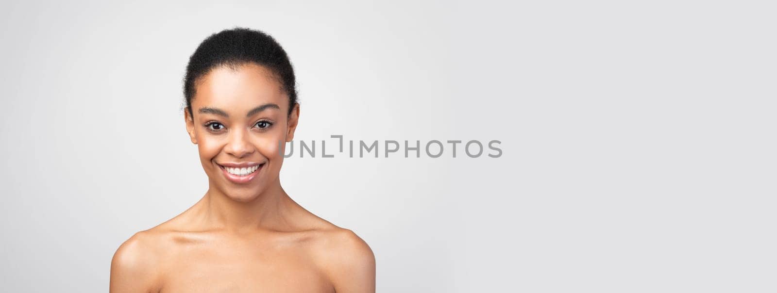 Female Beauty Portrait. Attractive African American Woman Smiling Looking At Camera Posing Shirtless Expressing Positive Emotions Over Gray Studio Background. Sensuality And Body Care, Copy Space
