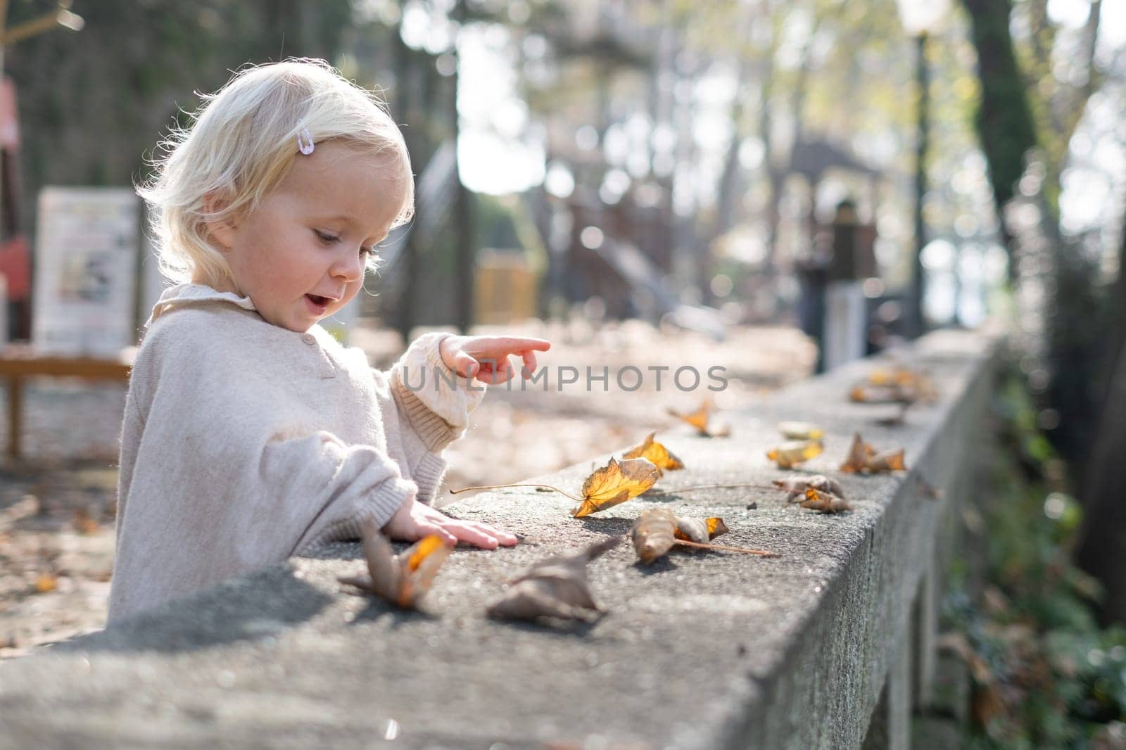 autumn outdoor portrait of beautiful happy child girl walking in park playing with leaves