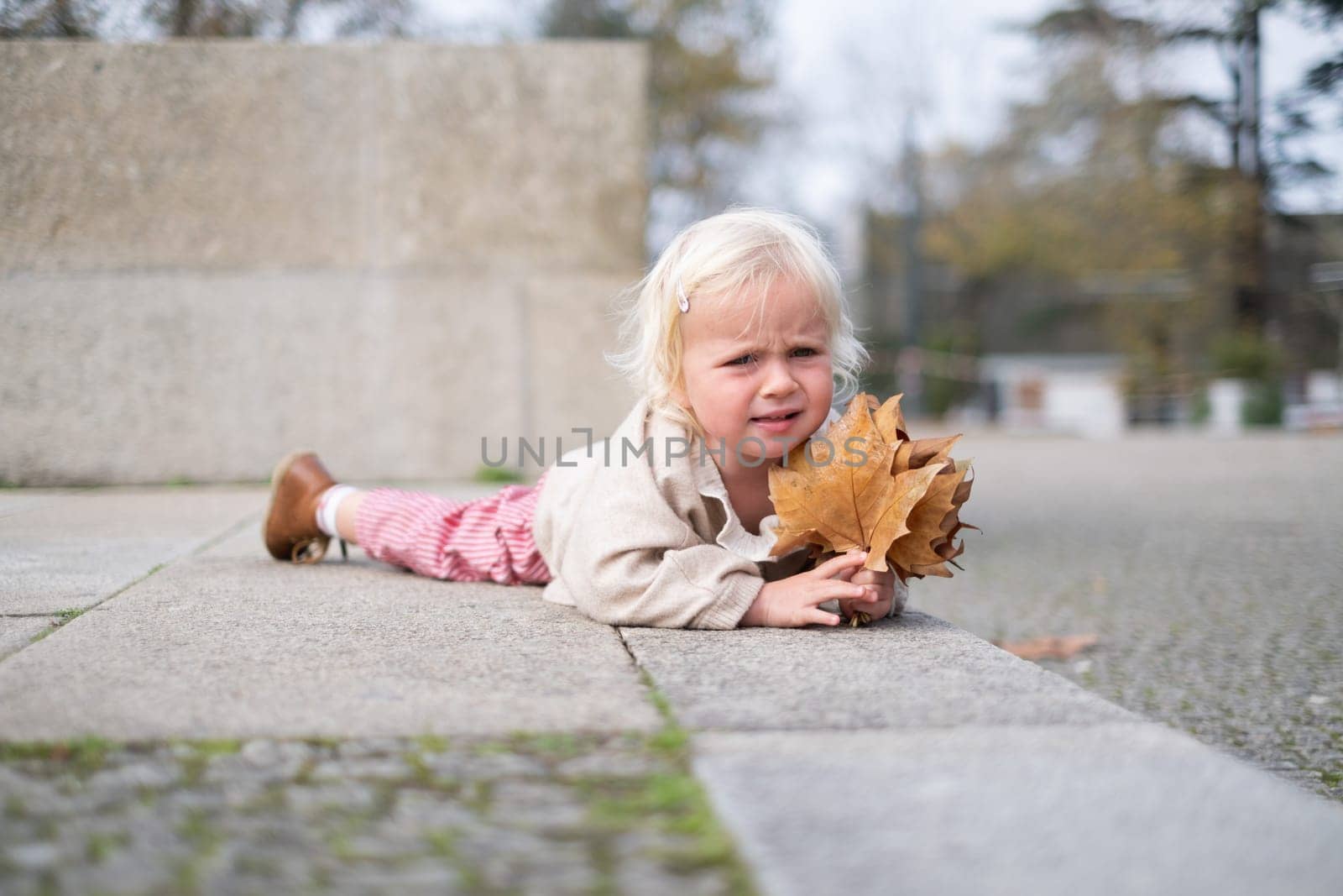 Portrait of a caucasian two years old baby girl crying outdoors. fell down