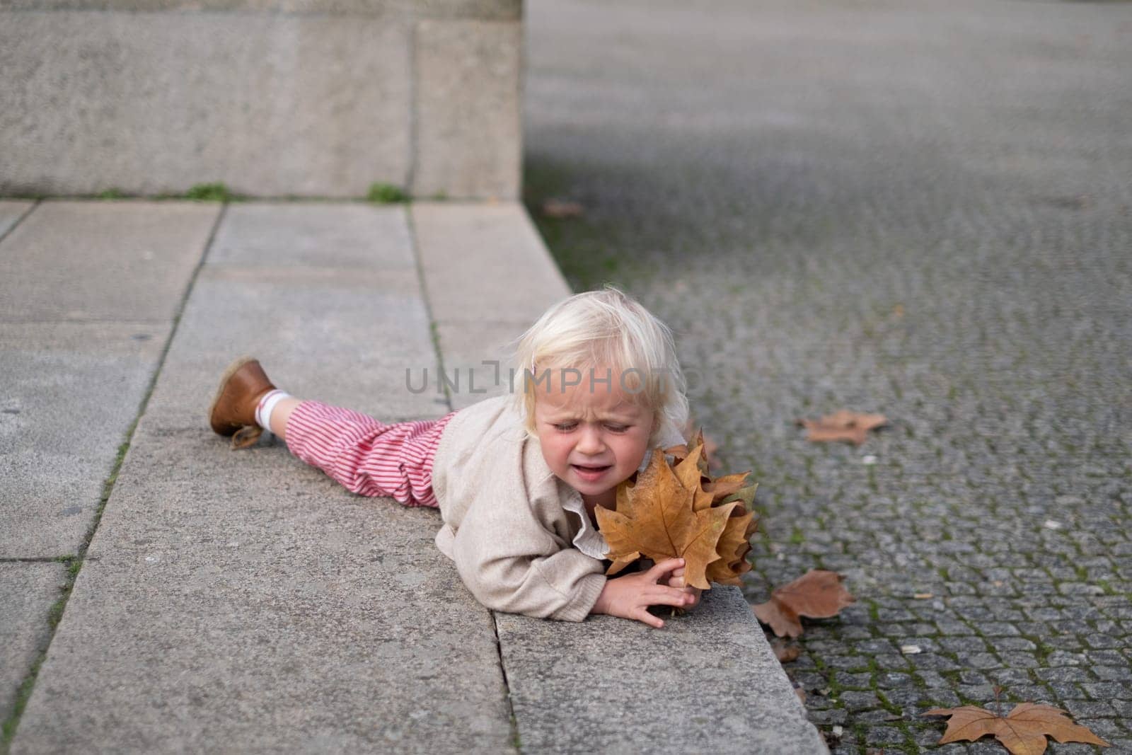 Portrait of a caucasian two years old baby girl crying outdoors. fell down
