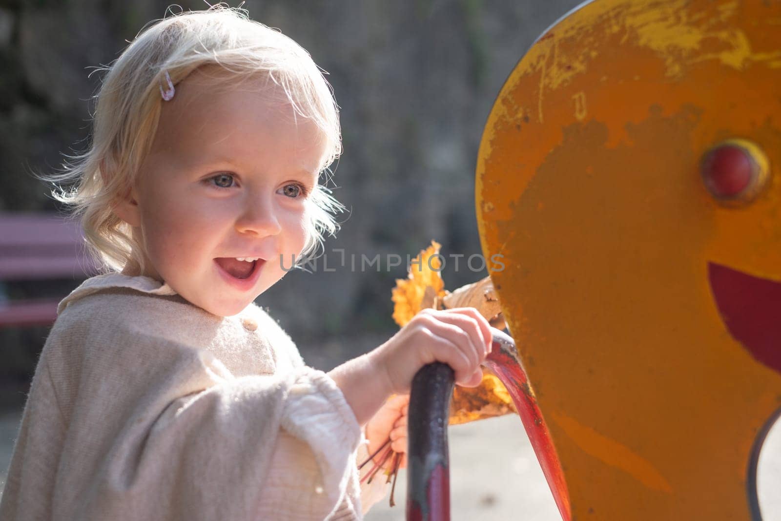 Portrait of a small little cute caucasian girl three years old thinking looking to the ground on the swing in the park