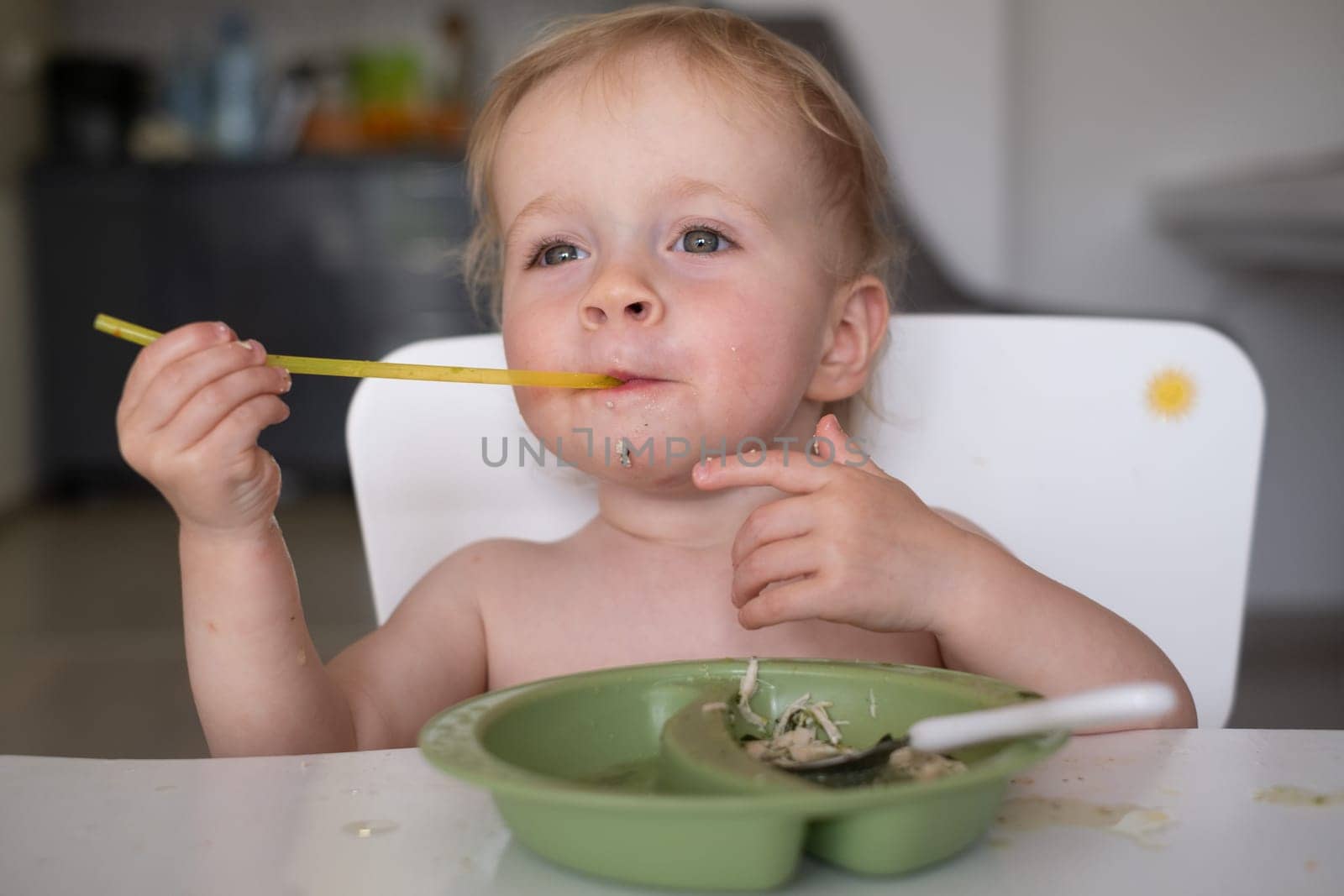 Hungry little kid eating soup with noodles with big spoon. High quality photo