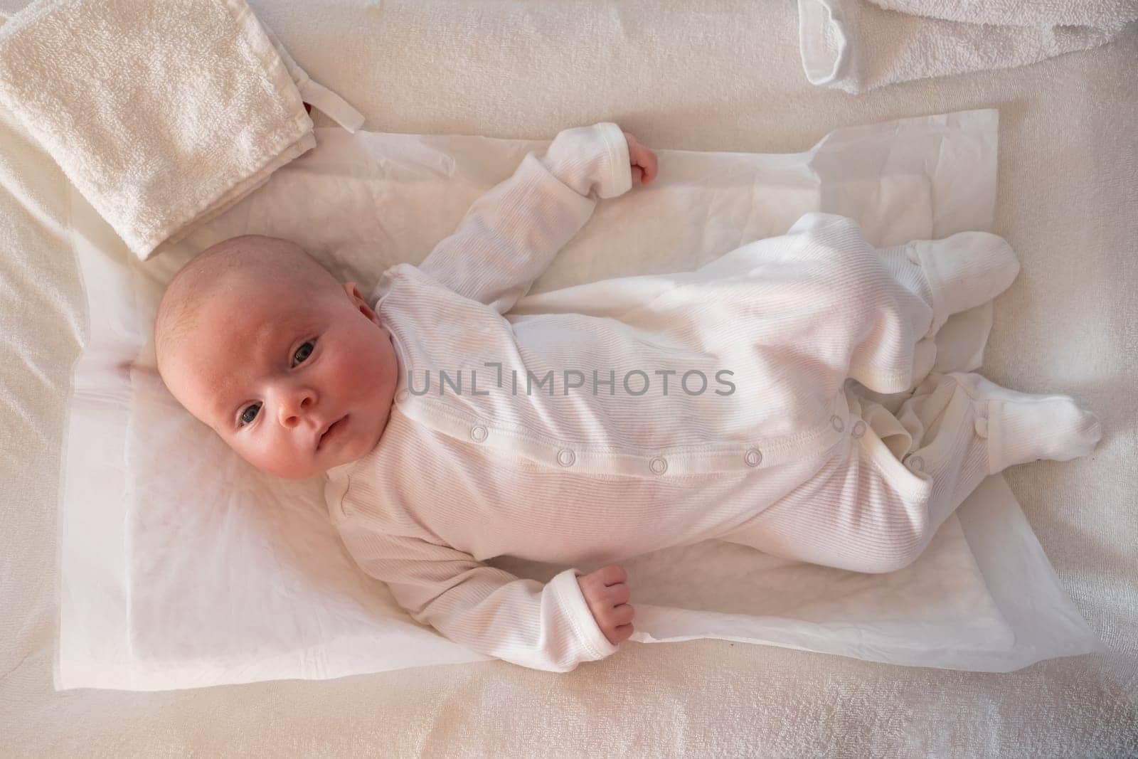 Cute small caucasian boy lying at bed looking at camera