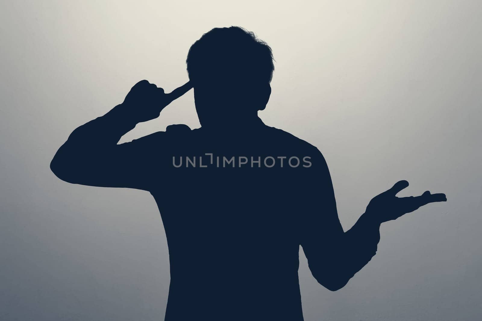 Angry young man t is gesturing with his finger against his temple, seemingly asking, Are you crazy.