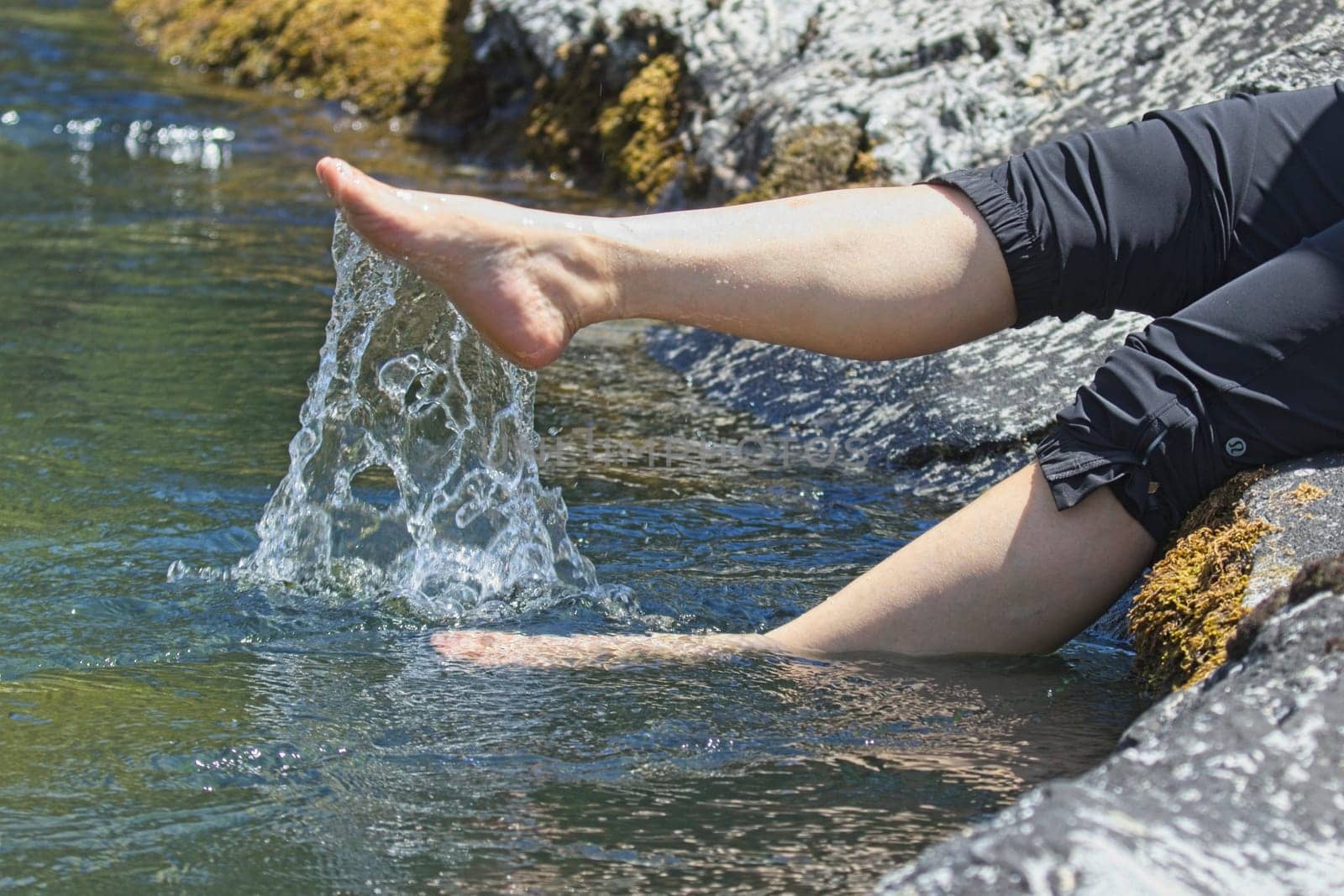 A concept lifestyle photo of the legs of a woman kicking up water from the river in north Idaho.