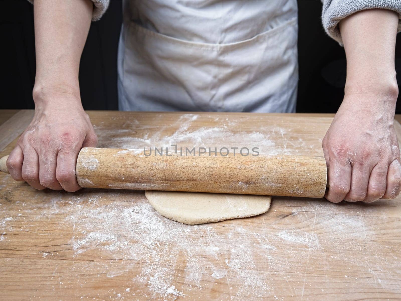 A concept photo of rolling out dough on a cutting board using a rolling pin.