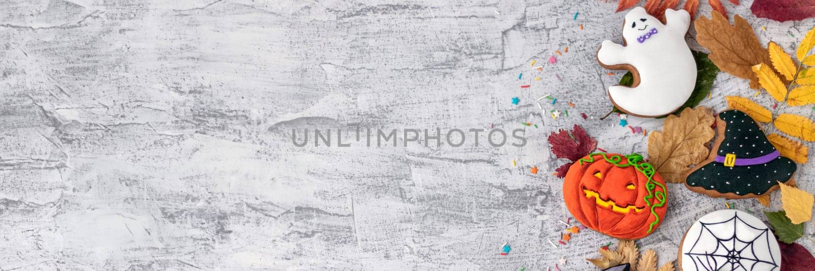 Banner of Halloween background with cookies, leaves, sunflowers and spiders, copy space. Halloween objects on textured concrete with space for text. Vintage background Halloween celebration. Flat lay Soft focus
