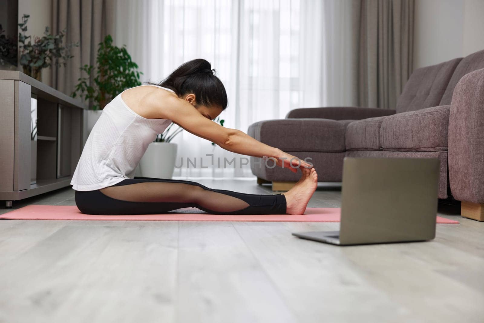 fit Caucasian woman worm up by stretching her body on pink exercise mat at home