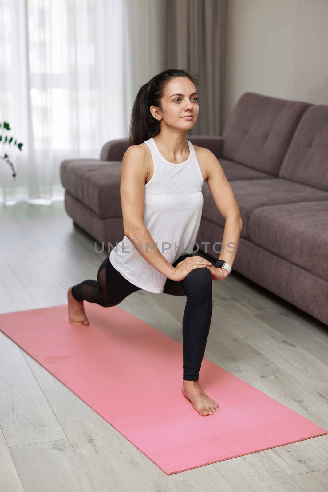fit woman in sportwear exercising at home, stretching legs.
