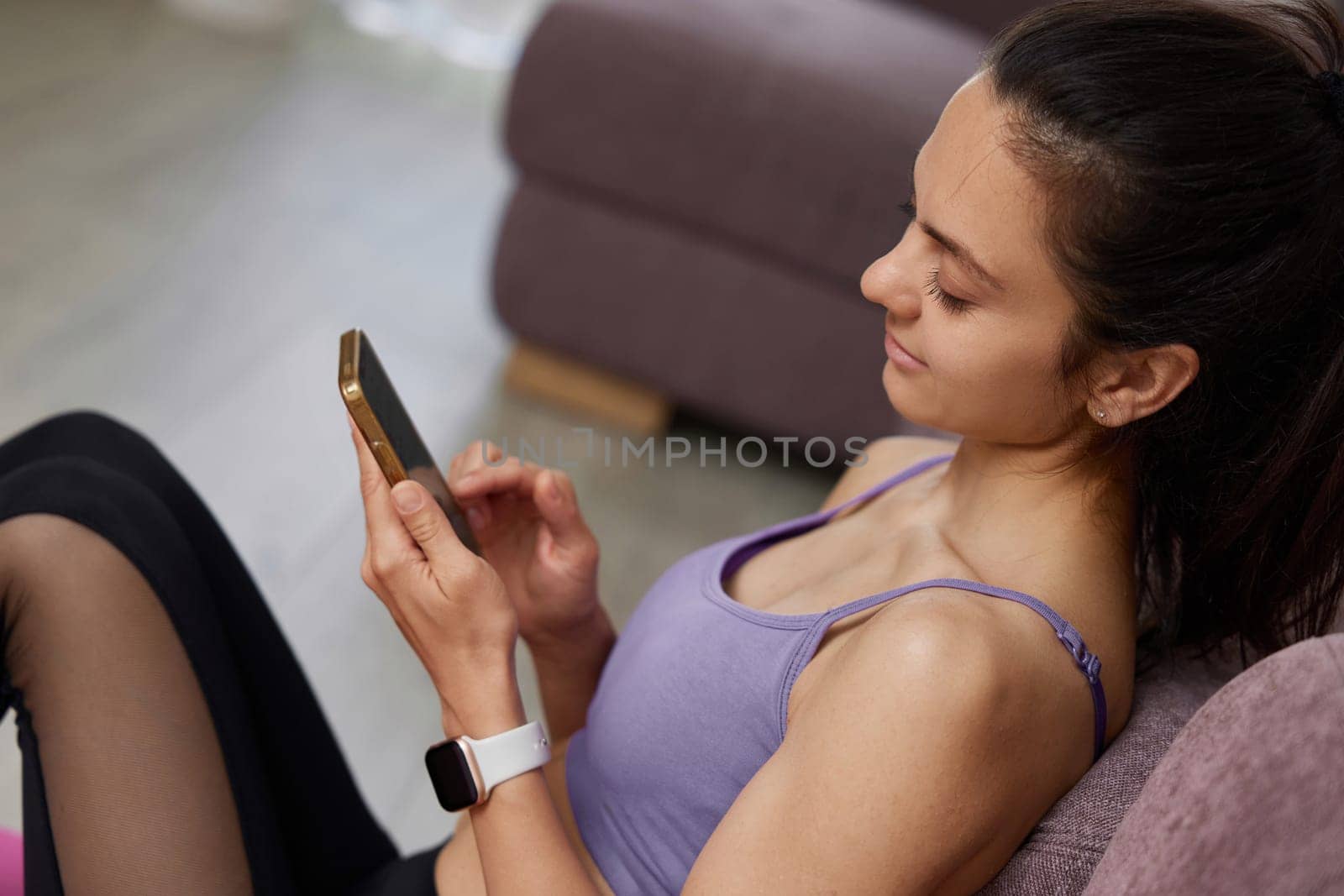 Caucasian sporty woman sitting and using smartphone at home