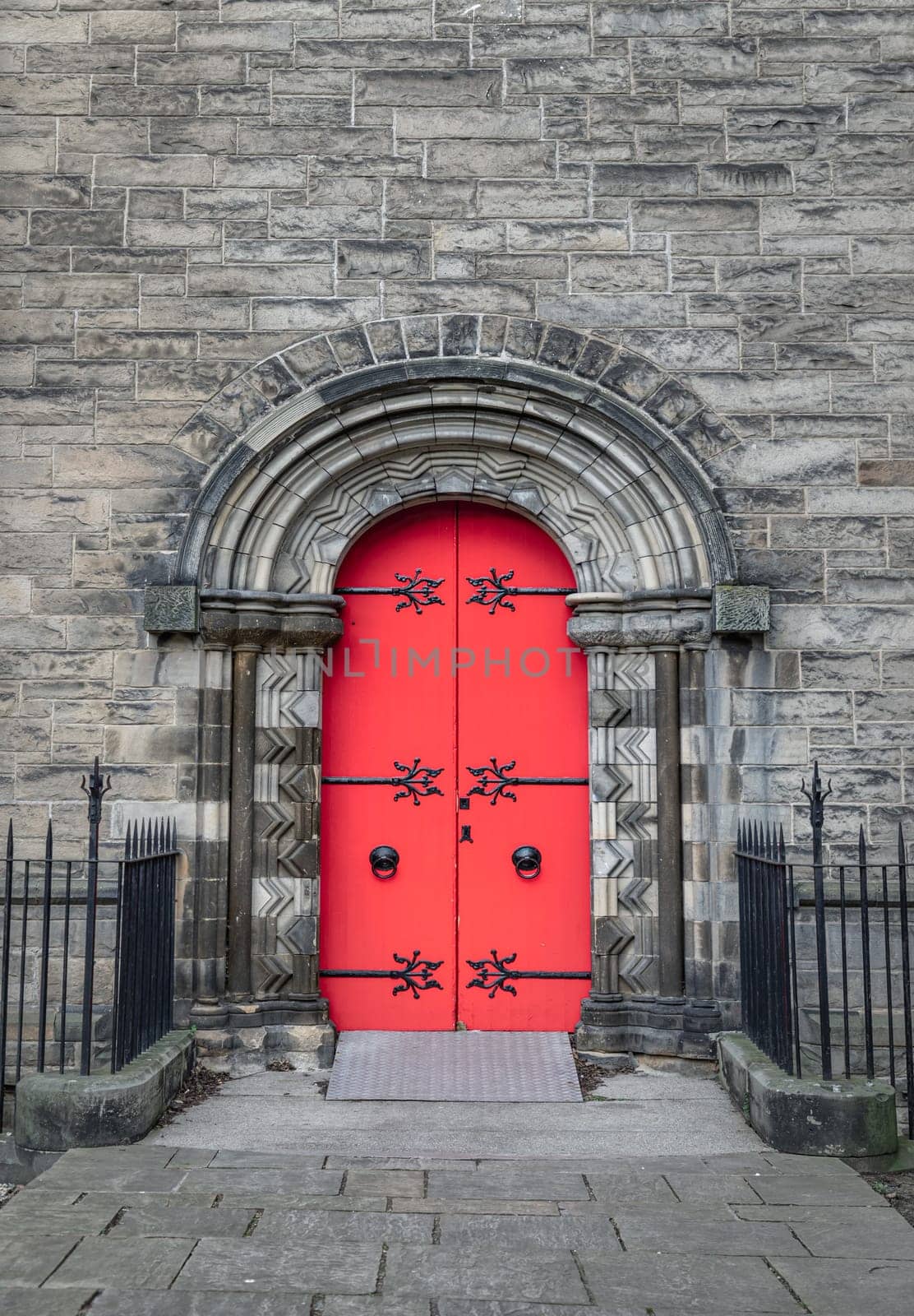 Edinburgh, Scotland - Jan 16, 2024 - Facade of arched red wooden doorway on stone wall of Mansfield Traquair Centre in Edinburgh. Scotland. Copy space, Selective focus.