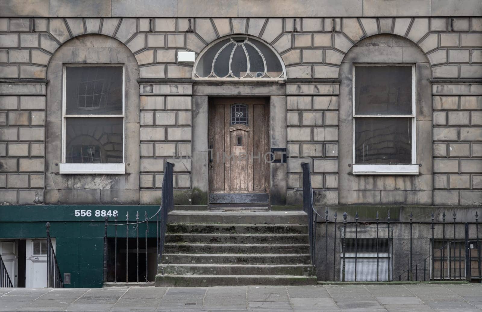 Edinburgh, Scotland - Jan 16, 2024 - Georgian architecture of House in Edinburgh. Facade of Traditional house with sash windows, wooden doorway, stone stairs and wrought iron black railings, Space for text, Selective focus.