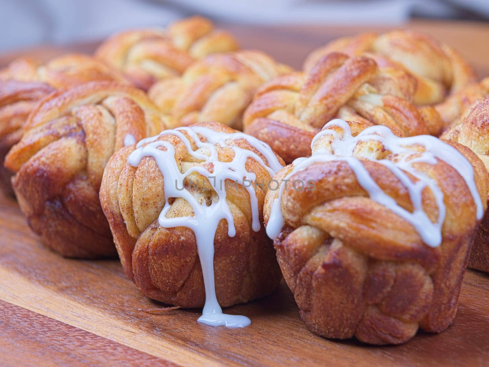 A close up of pouring glaze on homemade braided cinnamon rolls.