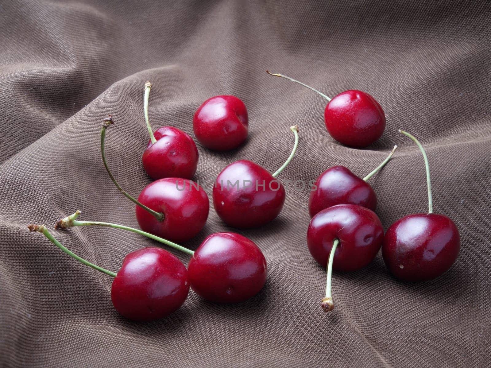 A close up photo of a bunch of cherries displayed on an old cloth.