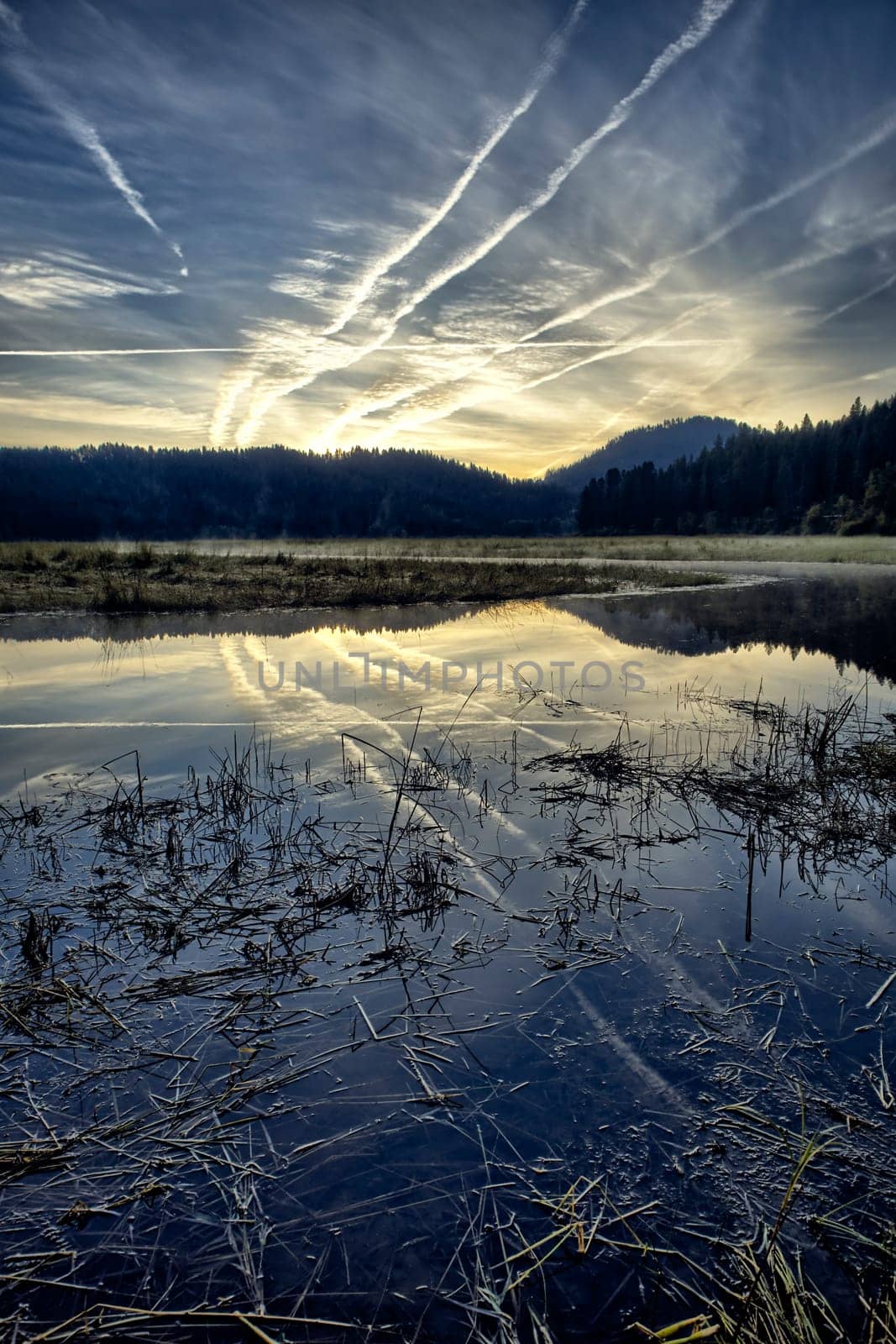 An early morning landscape photo of the sky and clouds reflecting off the calm St. Joe River near St. Maries, Idaho.