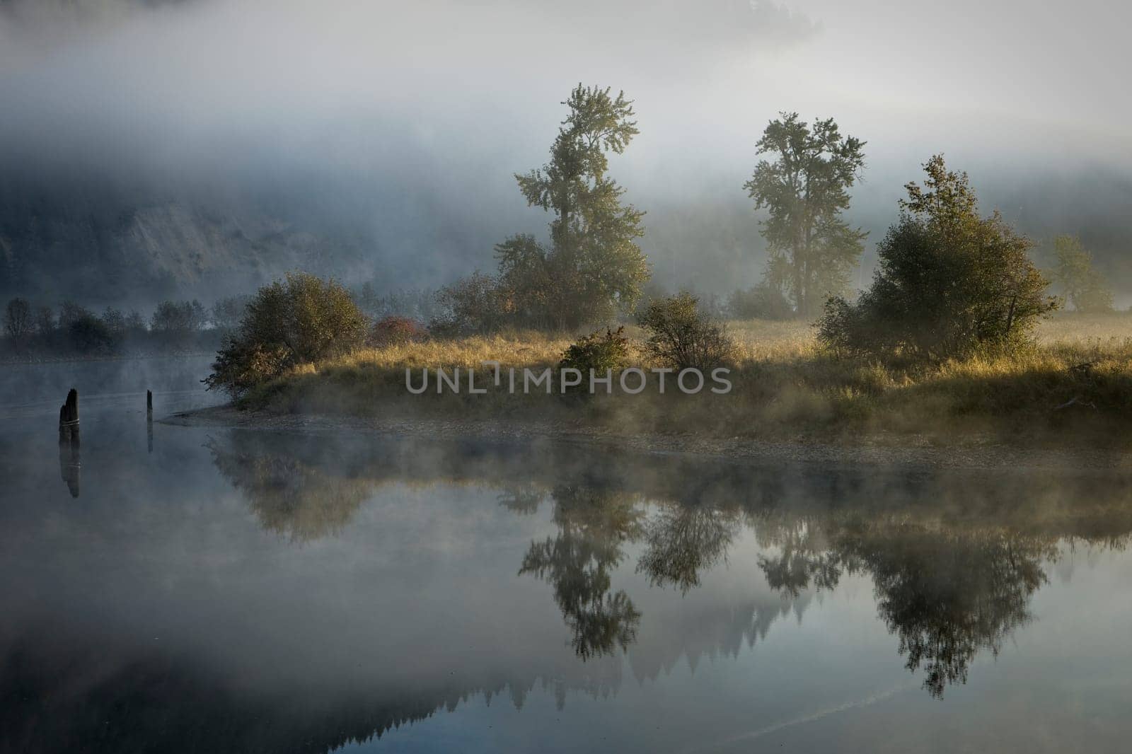 Fog  and mist layers lightly covers the calm mirror like St. Joe River near St. Maries, Idaho.