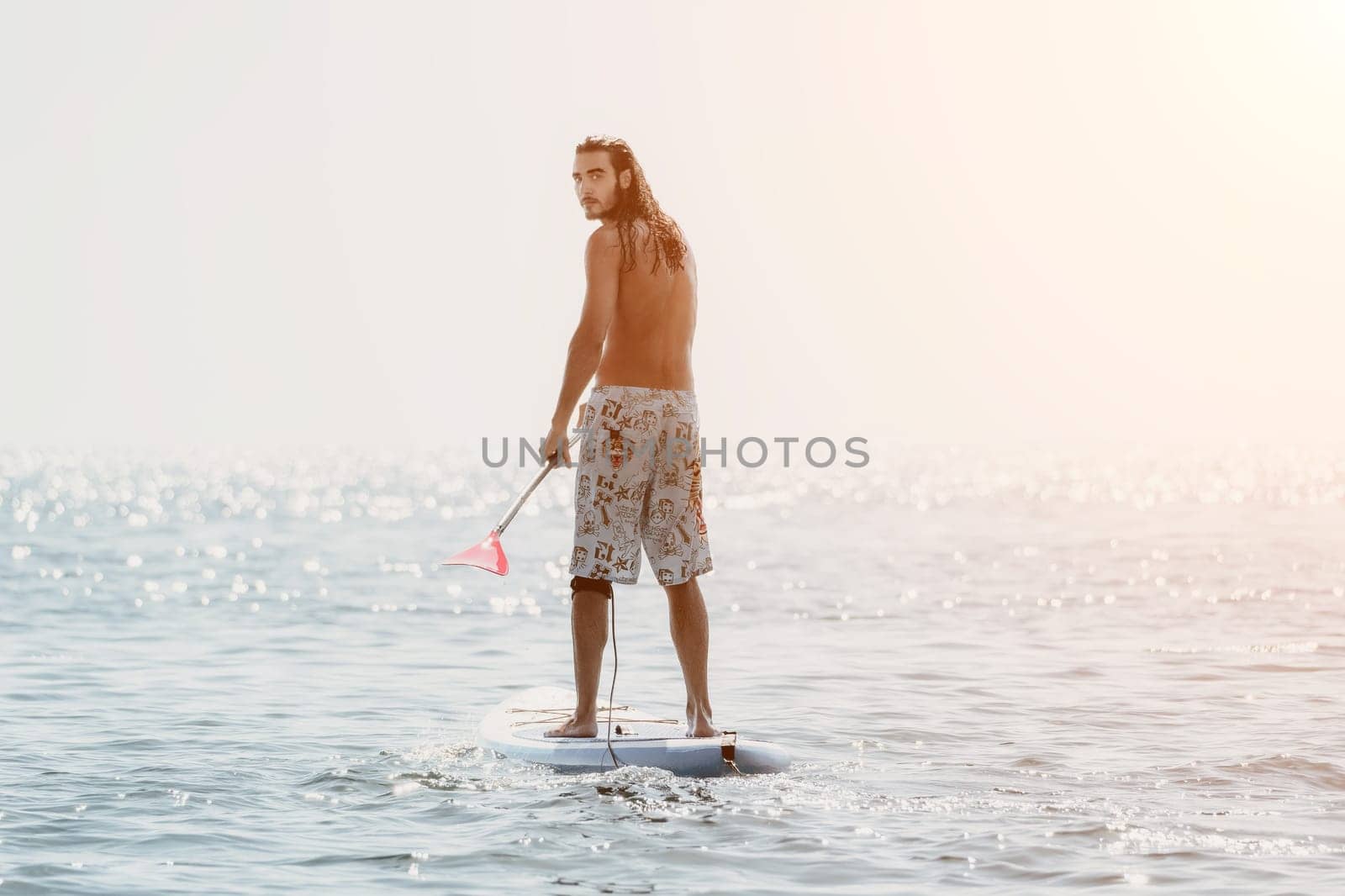 Man Sea Sup. Strong athletic man learns to paddle sup standing on board in open sea ocean on sunny day. Summer holiday vacation and travel concept. Aerial view. Slow motion.