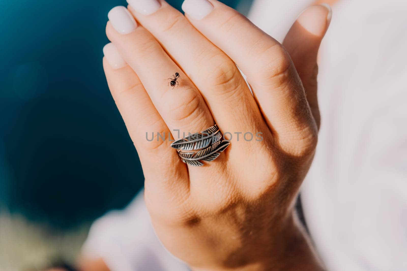 A woman is holding a ring with feathers on it. The ring is on her finger and she is looking at it