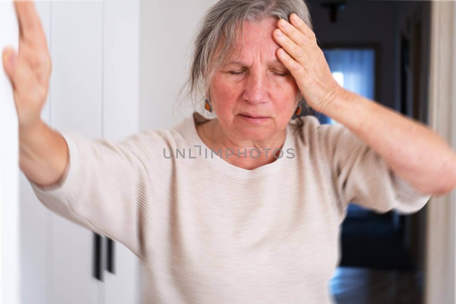 Unhappy mature woman touching head, feeling strong headache, at home alone, upset older female suffering from migraine or high blood pressure