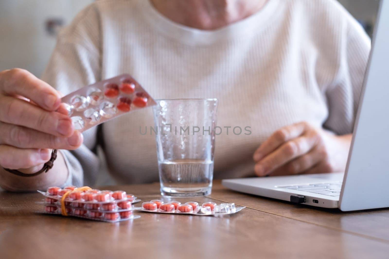 Senior woman takes pill with glass of water in hand. Stressed female drinking sedated antidepressant meds. Woman feels depressed, taking drugs.