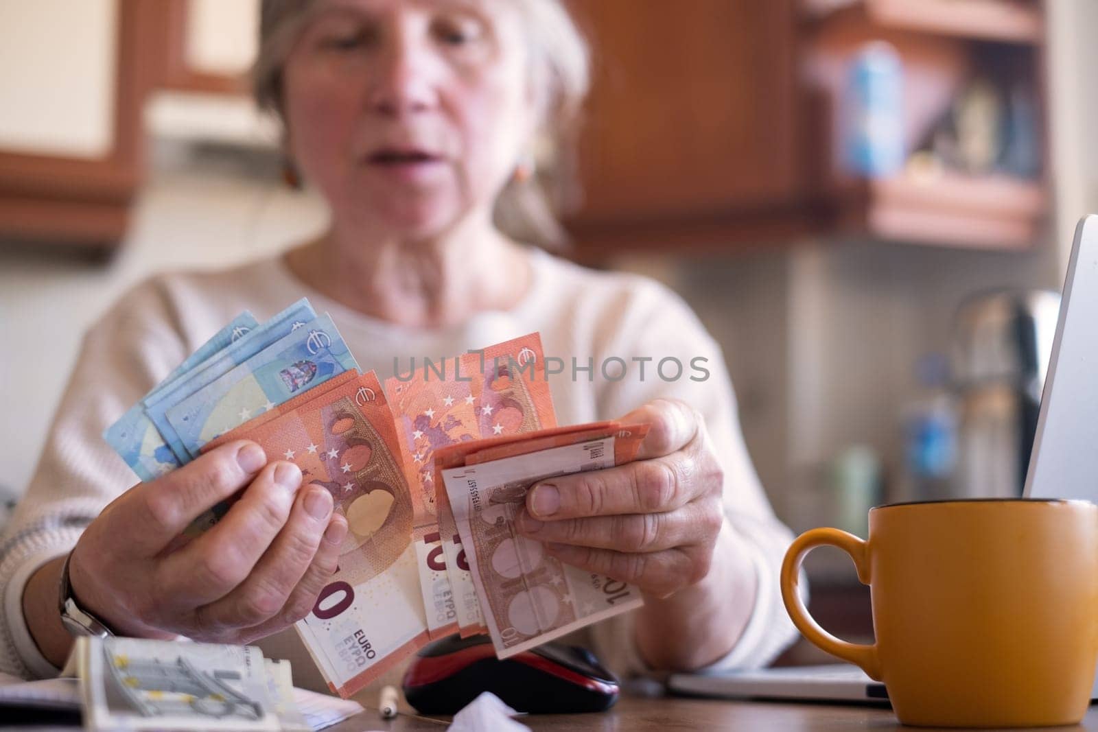 Portrait of an old woman counting money. The concept of old age, poverty, austerity.
