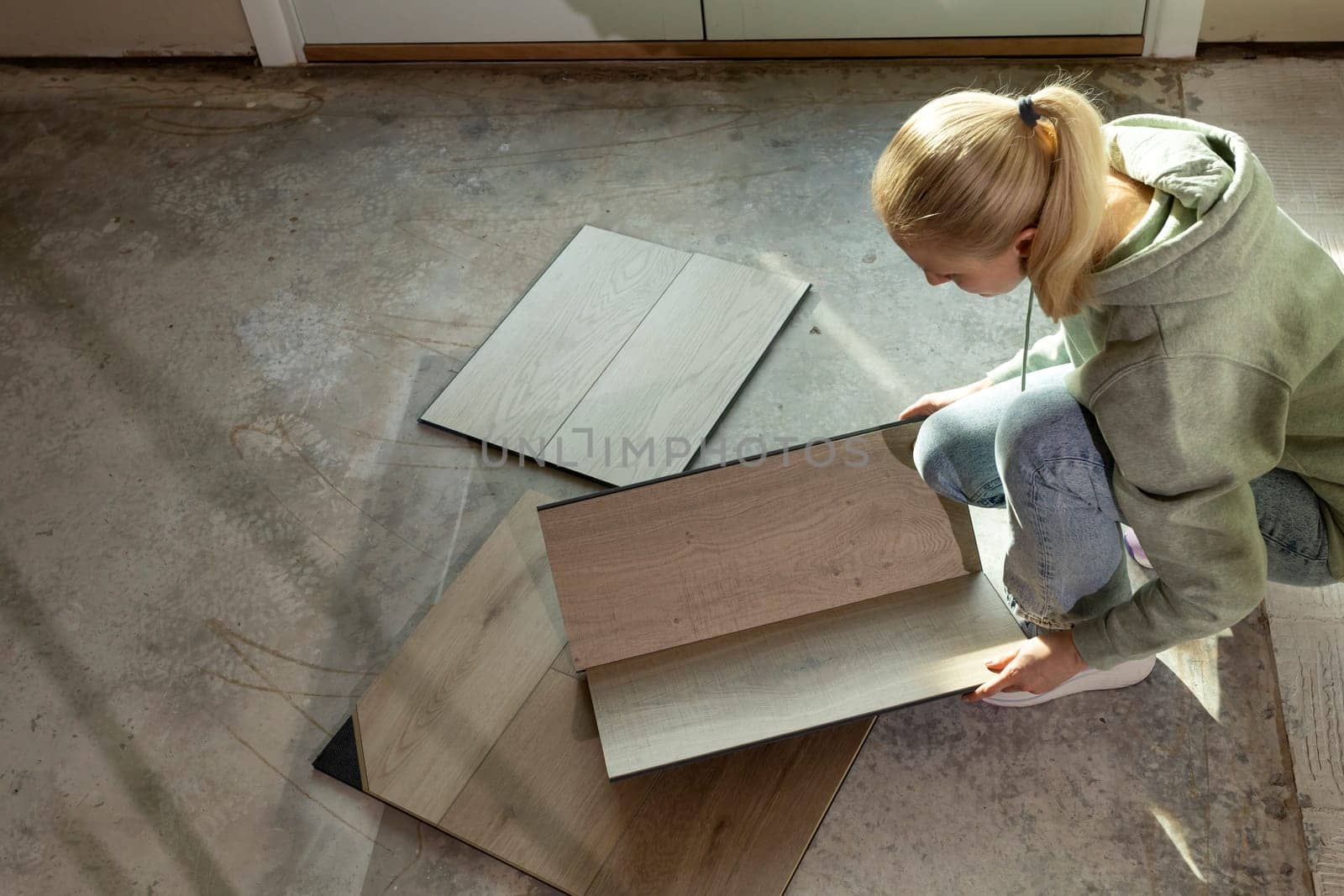 Interior Decorator Holds Luxury Vinyl Wood Samples On Concrete Floor In Condo. Selecting Waterproof Flooring. Home Reconstruction. Vinyl Tiles Collection, Patterns. Interior Design Idea. Horizontal