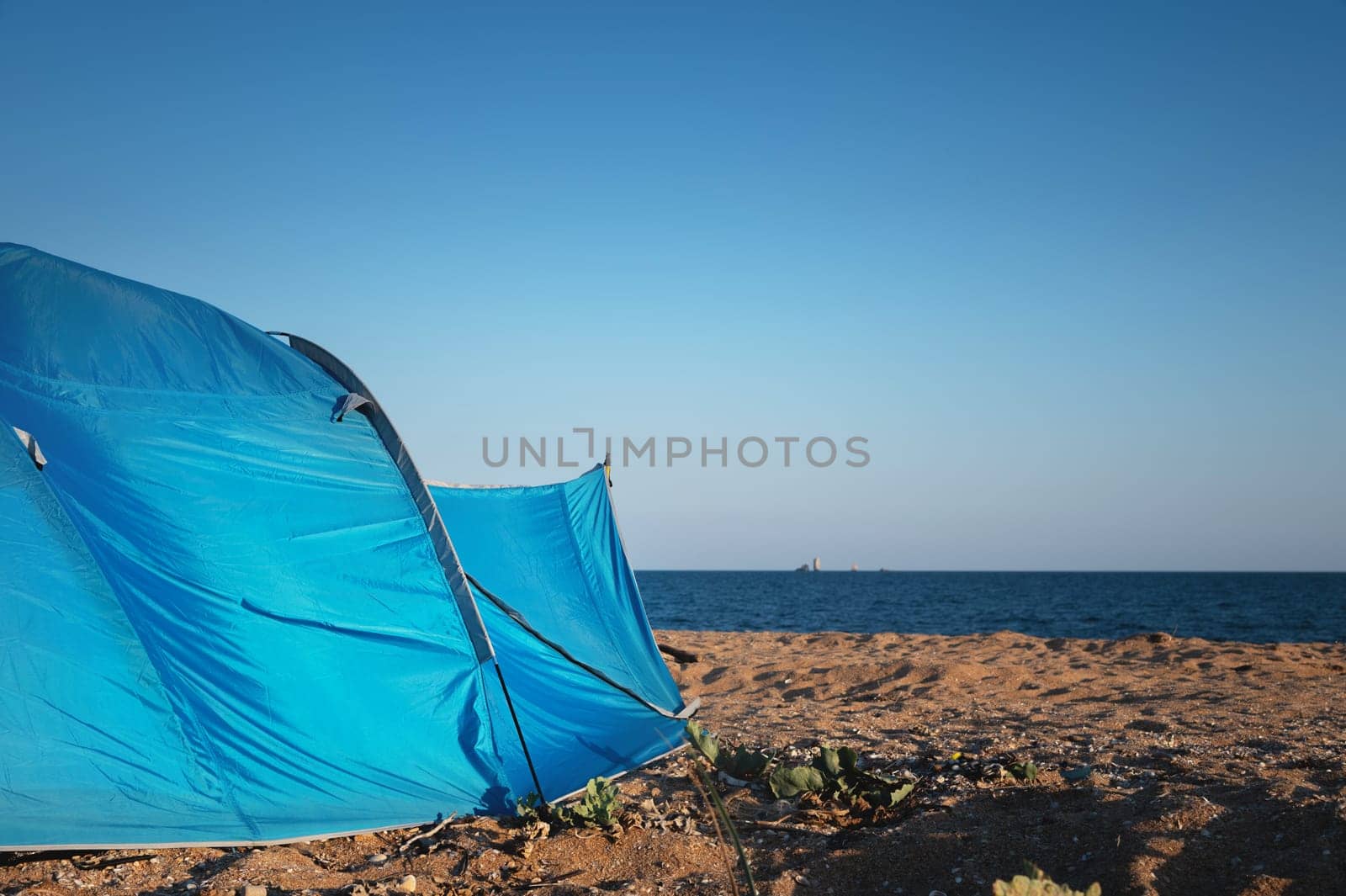 Tent on the sandy beach by the sea. Nobody. A colorful tent to protect from the wind, the sun and to sleep in.