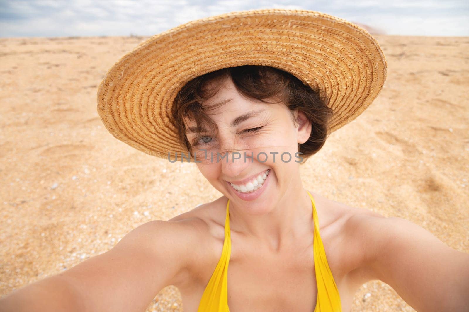 Happy girl taking selfie during summer beach vacation smiling with fun during tropical caribbean vacation. Caucasian woman holding a phone with a camera taking a photo of herself.