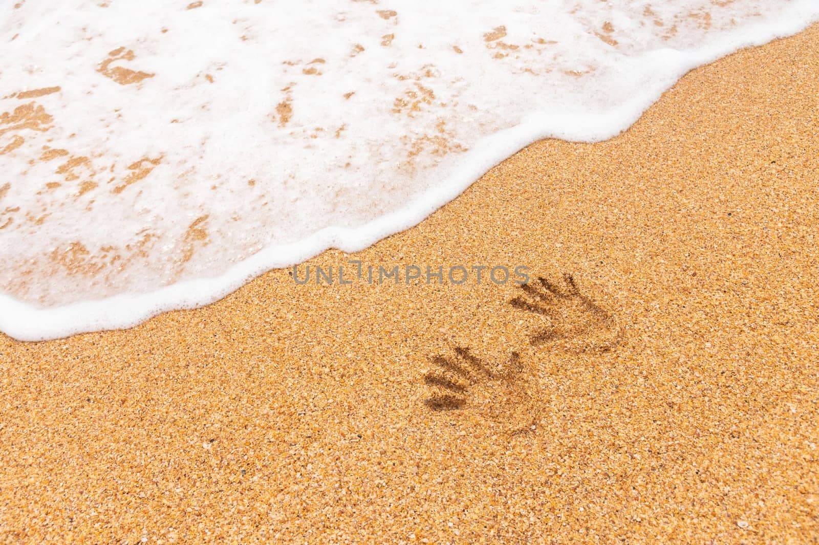 Two human palm prints in the sand. Sandy coast and oncoming wave by yanik88