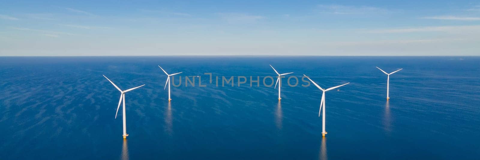 offshore windmill park with clouds and a blue sky, windmill park in the ocean aerial view with wind turbine Flevoland Netherlands Ijsselmeer.