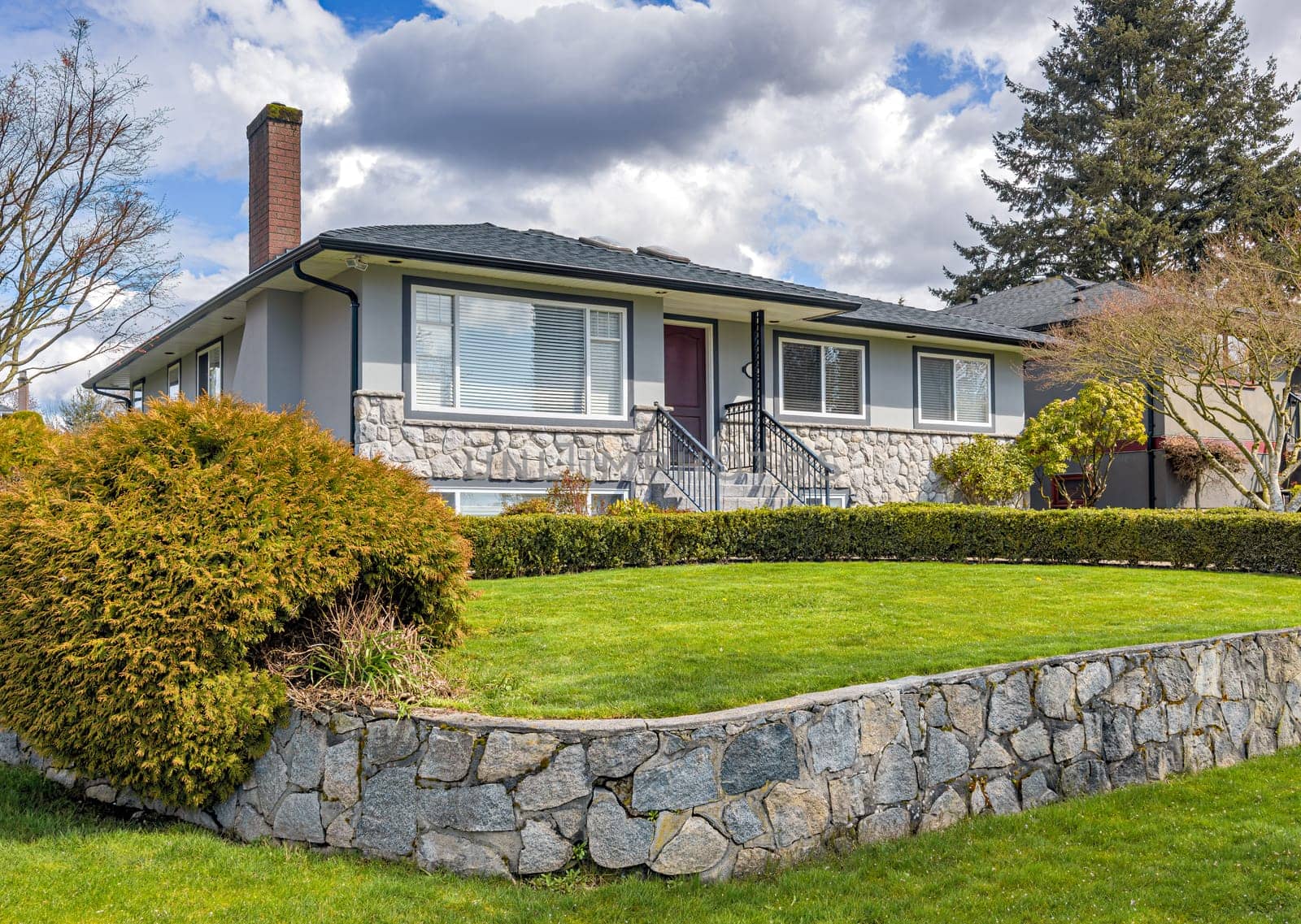 Average residential house with green lawn on land terrace in front.