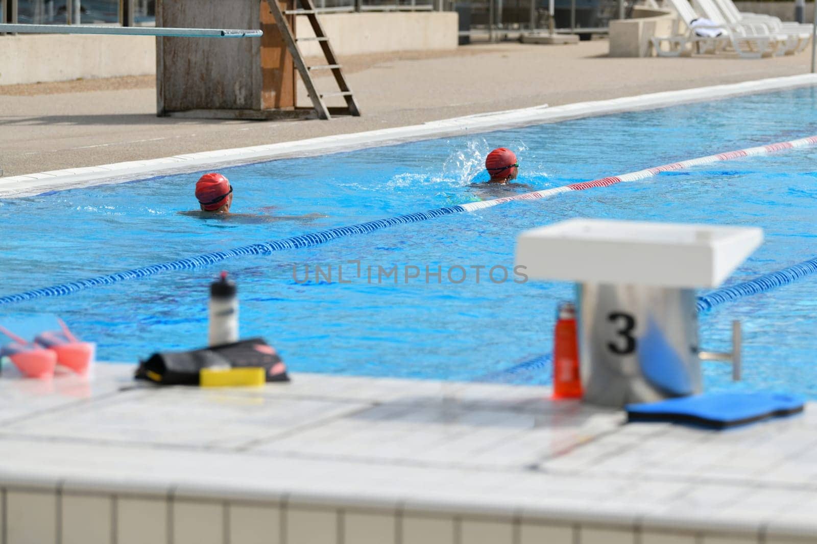 Swimmers wearing silicone caps compete in a pool