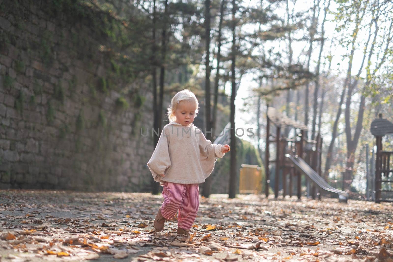 autumn outdoor portrait of beautiful happy child girl walking in park playing with leaves
