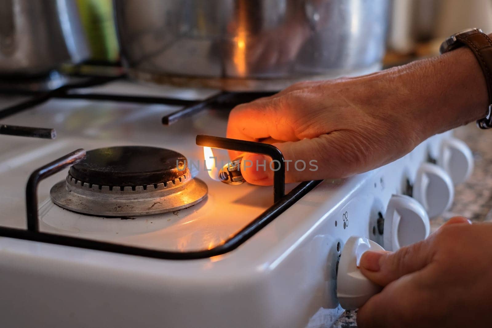senior hand adjusting gas burning from a kitchen gas stove.