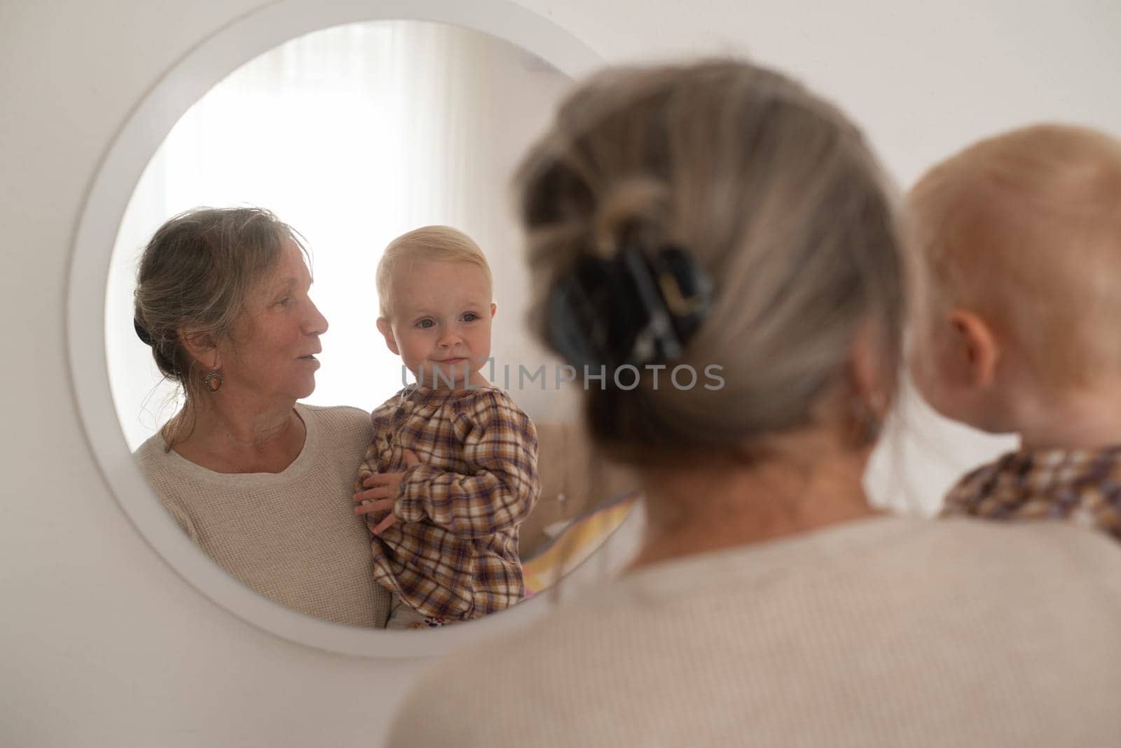 A cute little girl and her grandmother looking at mirror spending time together