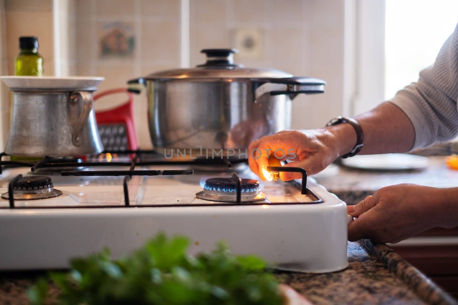 senior hand adjusting gas burning from a kitchen gas stove.
