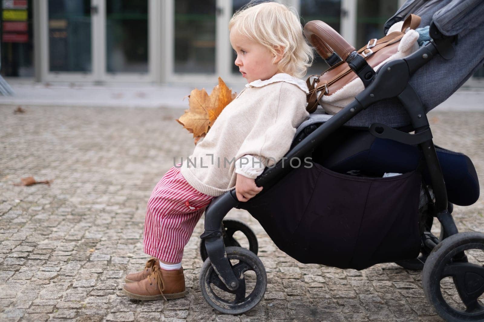 Little baby girl sitting in a chair in a baby carriage being tired