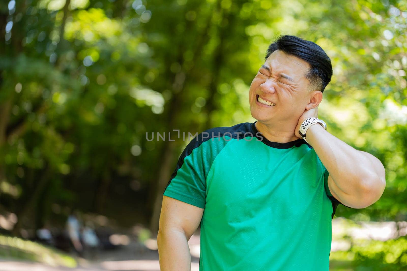 Sport Asian jogger man have shoulder pain, injury concept. Fitness muscular Japanese male has neck pain and shoulders after running having an ache in his arm. Athlete runner pain in joints outdoors.