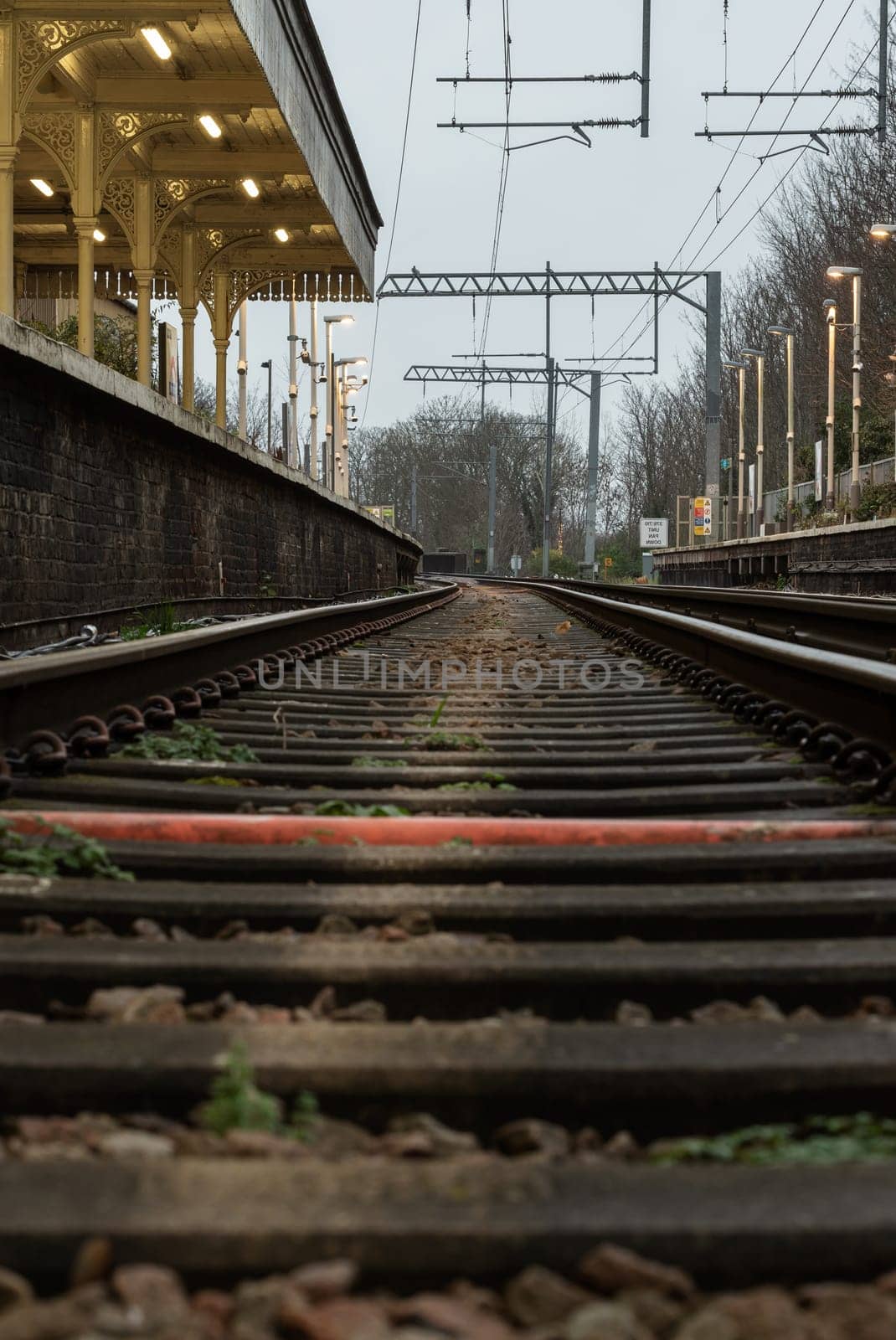 London, UK - Dec 25, 2023 - Railway iron rails from the low perspective. Railroad tracks with limited depth of focus, The Railway system with Metal frames of Train platform, Railroad track rails, Train tracks, Railway station, Space for text, Selective focus.