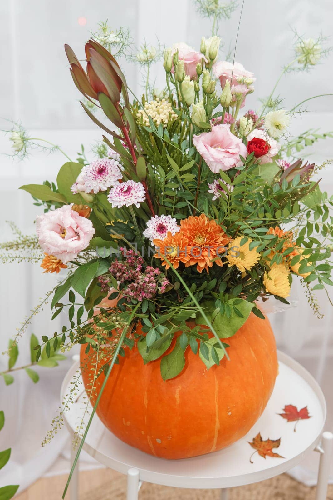 Flower arrangement in a pumpkin, autumn interior decor. Creating handmade autumn decor