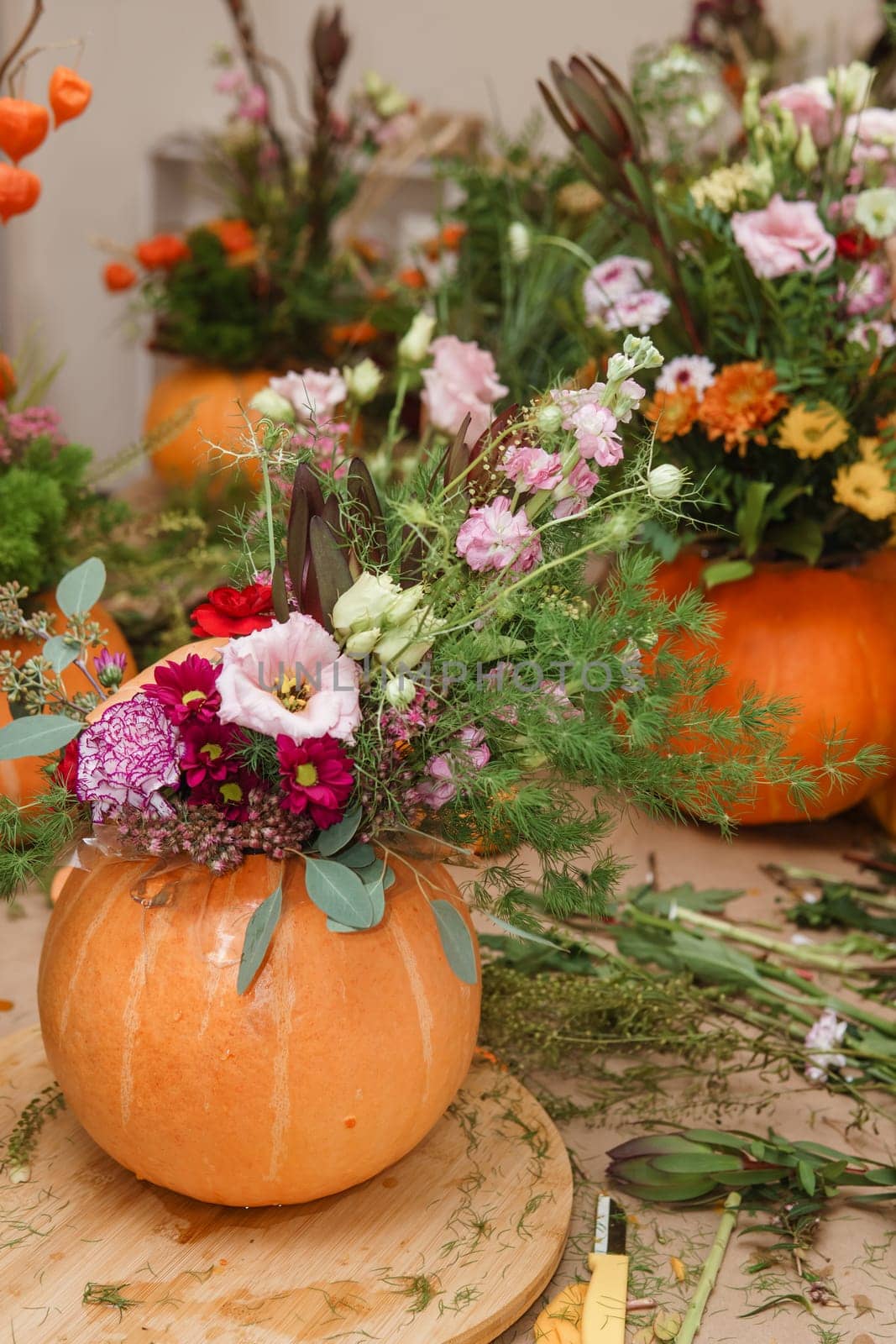 Flower arrangement in a pumpkin, autumn interior decor. Creating handmade autumn decor
