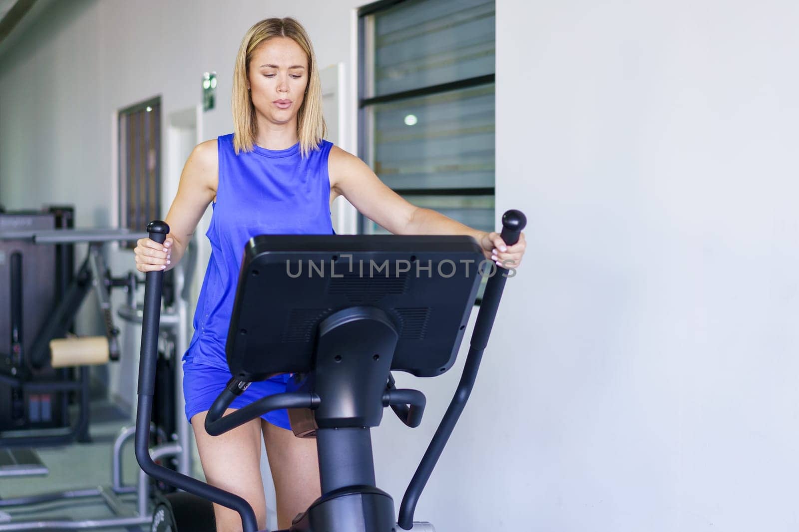 Fit serious caucasian woman on elliptical trainer at gym