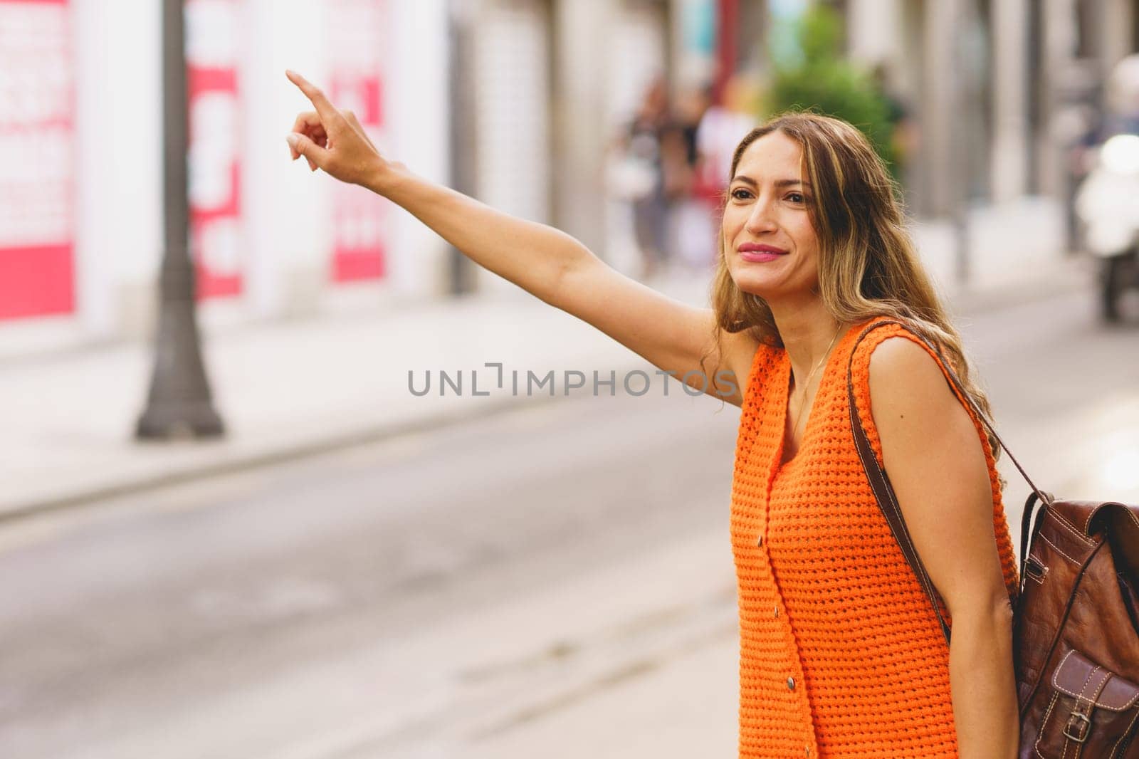 Latin businesswoman wearing business casual clothing hailing a taxi ride in the city