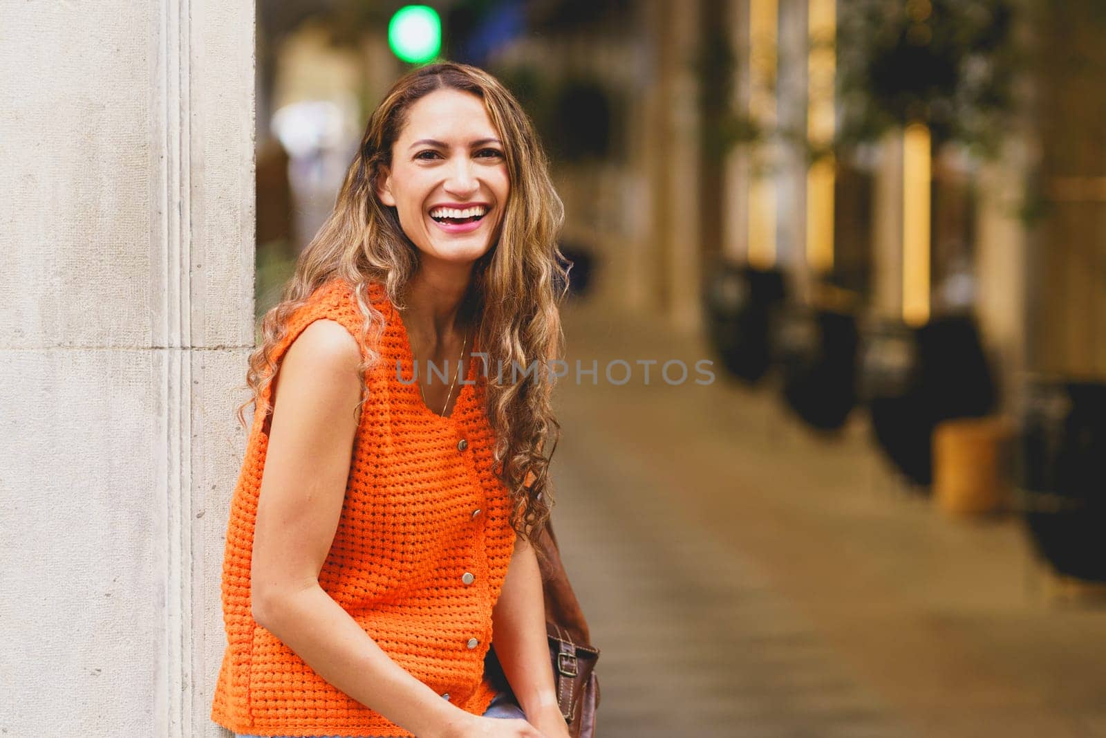 Happy latin beauty woman laughing at the camera sitting in the street